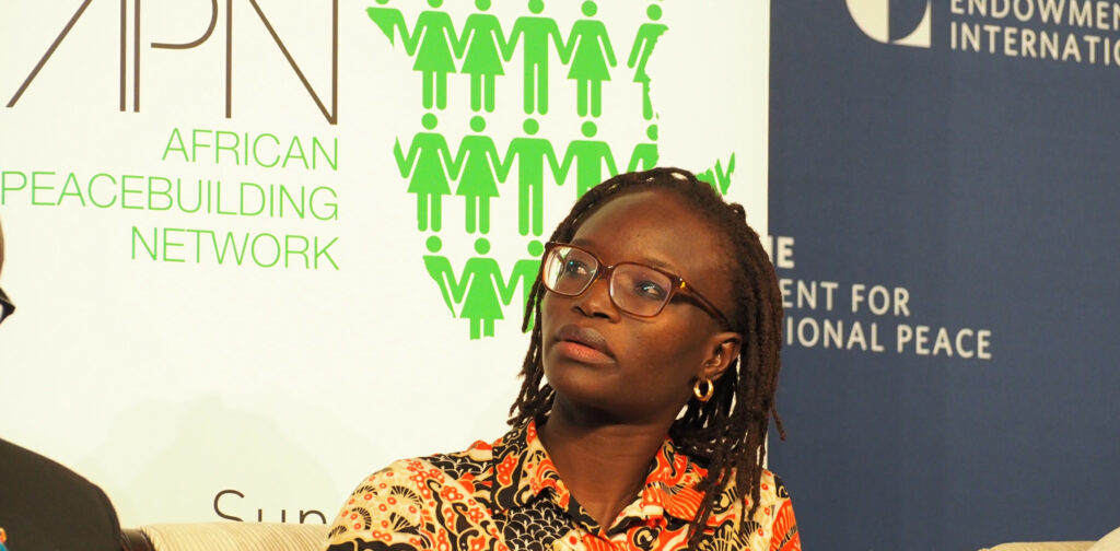 Dr. Amy Niang sitting on a panel at the Carnegie Endowment for International Peace with APN and Carnegie banners behind her.